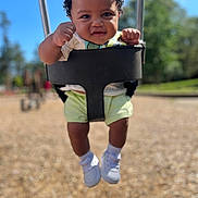 Jaiteek is registered to the contest to win money with this photo: toddler, child, swing, playground, outdoor, happy, smiling, curly_hair, white_shoes, shorts, sunny, daylight, blurred_background, fists, baby, seat, park, fun, cute, person