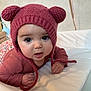baby, child, knitted_hat, pink_hat, bear_ears, infant, cute, portrait, closeup, face, eyes, hands, clothing, lying_down, soft_surface, indoors, warm, cozy, expression, person