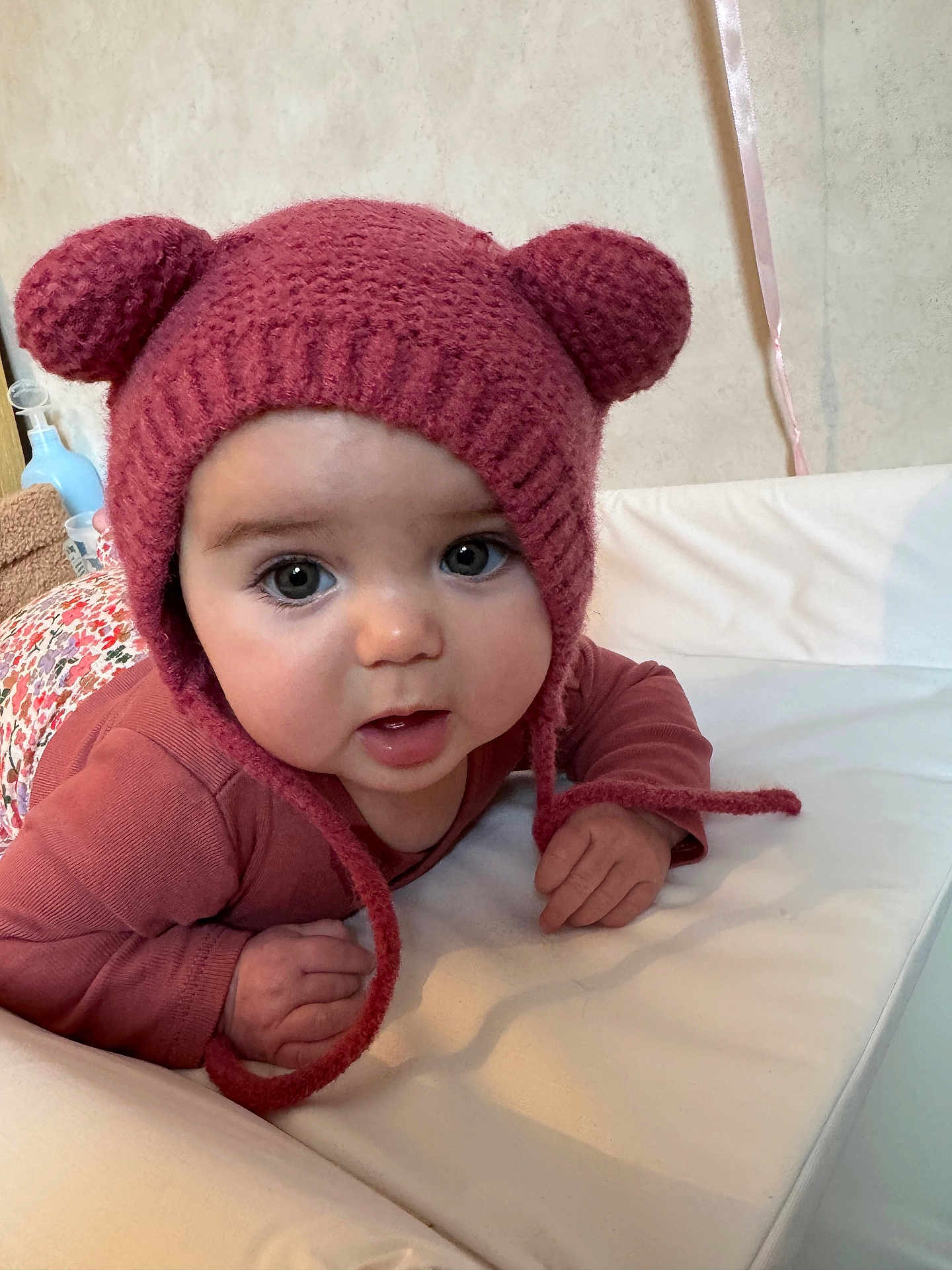 Alma participe au concours pour gagner de l'argent avec cette photo : baby, child, knitted_hat, pink_hat, bear_ears, infant, cute, portrait, closeup, face, eyes, hands, clothing, lying_down, soft_surface, indoors, warm, cozy, expression, person