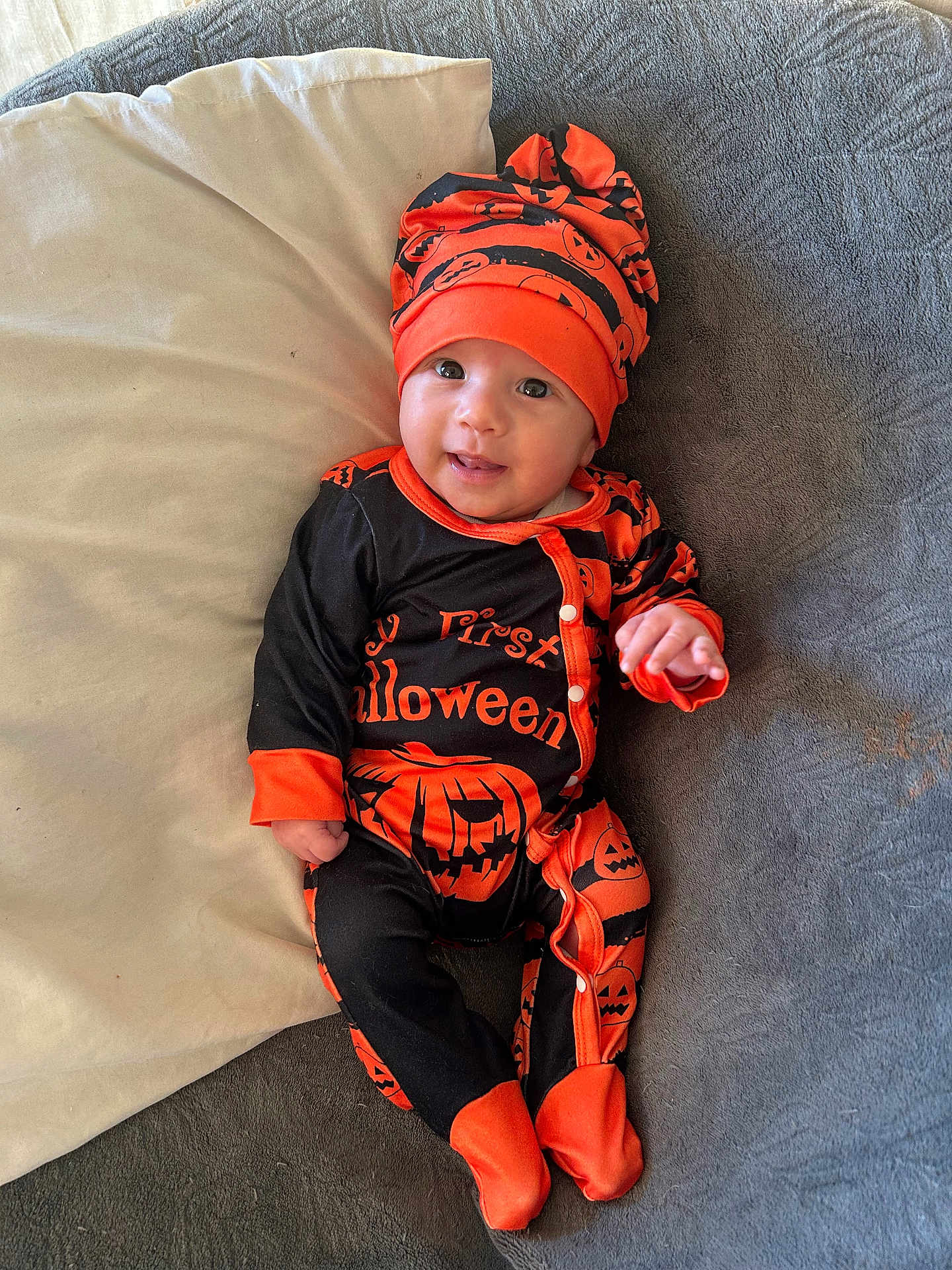 Gabriel participe au concours pour gagner de l'argent avec cette photo : baby, infant, child, halloween, costume, hat, smile, lying_down, blanket, pillow, orange, black, cute, happy, footed_pajamas, jack_o_lantern, one_person, indoors, portrait, apparel
