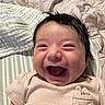 baby, infant, child, smiling, laughing, portrait, close_up, face, dark_hair, pink_outfit, cat_pocket, bed, blanket, bedding, indoor, nursery, lying_down, happy, adorable, photography