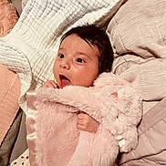 Charlotte is registered to the contest to win money with this photo: baby, infant, child, portrait, indoors, bed, blanket, pillows, pink, fluffy, clothing, satin, sleeping, lying_down, wide_eyed, open_mouth, dark_hair, cozy, home, photography
