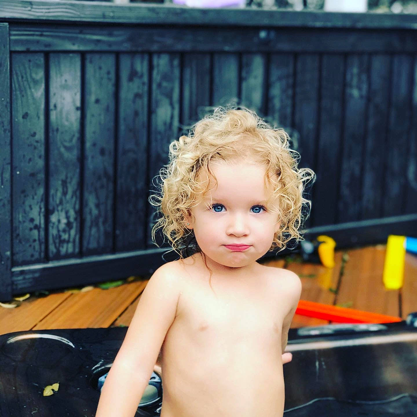 Leighton is registered to the contest to win money with this photo: bathing, blond, chest, child, eye, eyebrow, eyelash, fence, flash_photography, fun, hairstyle, happy, head, human_body, leisure, neck, person, skin, smile, toddler