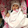 baby, child, stroller, blanket, hat, pink, floral_pattern, clothing, person, cute, infant, indoor, seat, comfort, toddler, warm, baby_clothes, headwear, expression, holding