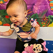 Gena is registered to the contest to win money with this photo: baby, toddler, child, smiling, sitting, plush_toy, minnie_mouse, colorful_background, wall_art, onesie, shorts, indoor, playtime, cute, happy, portrait, hair, cheek, arm, toy