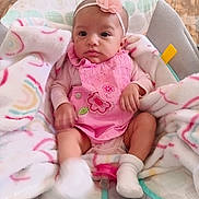 Gena is registered to the contest to win money with this photo: baby, baby_seat, blanket, child, clothing, comfort, cute, flower, headband, indoor, infant, pacifier, pattern, pink_dress, portrait, sitting, sock, soft_toy, wooden_floor, young_child