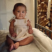 Alisson joined the competition — help win amazing prizes! baby, child, infant, dress, sitting, blanket, furniture, indoors, portrait, cute, smile, person, young, skin, face, hand, foot, cozy, lighting, texture