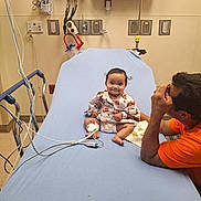 Marissa joined the competition — help win amazing prizes! baby, hospital, hospital_bed, medical_equipment, patient, adult, person, gown, monitoring_device, bed, blue_sheet, smile, sitting, lying_down, cables, medical_care, room, healthcare, concern, indoor