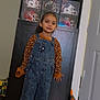Marielys is registered to the contest to win money with this photo: casual_clothing, child, denim_overalls, display_cabinet, door, floor_vent, girl, happy, helmet_collection, home, indoor, leopard_print, long_sleeve_shirt, person, pillow, smile, socks, sports_helmets, standing, wooden_floor