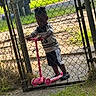 Jaderrion joined the competition — help win amazing prizes! child, scooter, gate, chain_link_fence, outdoor, grass, pavement, black_clothing, white_clothing, shoes, play, daylight, residential, yard, hair, person, toy, sidewalk, fence_post, backyard