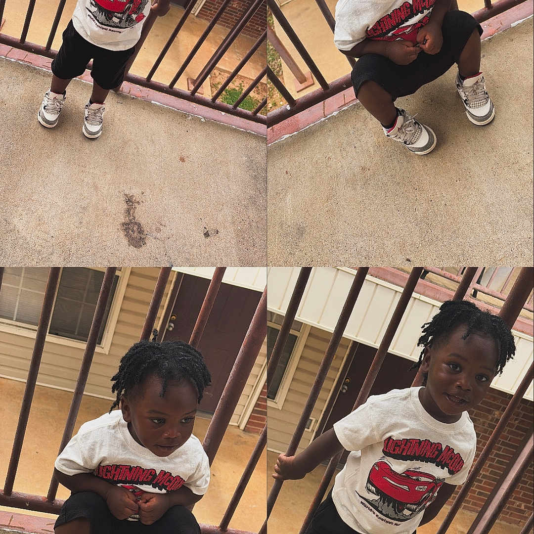 Jaderrion is registered to the contest to win money with this photo: child, smiling, toddler, clothing, tshirt, sneakers, outdoor, balcony, railing, concrete, happy, person, portrait, cute, young, playful, standing, squatting, black_hair, casual