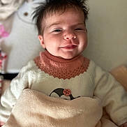 émy participe au concours pour gagner de l'argent avec cette photo : baby, smiling, blanket, cozy, sweater, pink_collar, penguin_design, face, hair, infant, soft_texture, closeup, indoor, cute, child, portrait, comfort, warm, happy, resting