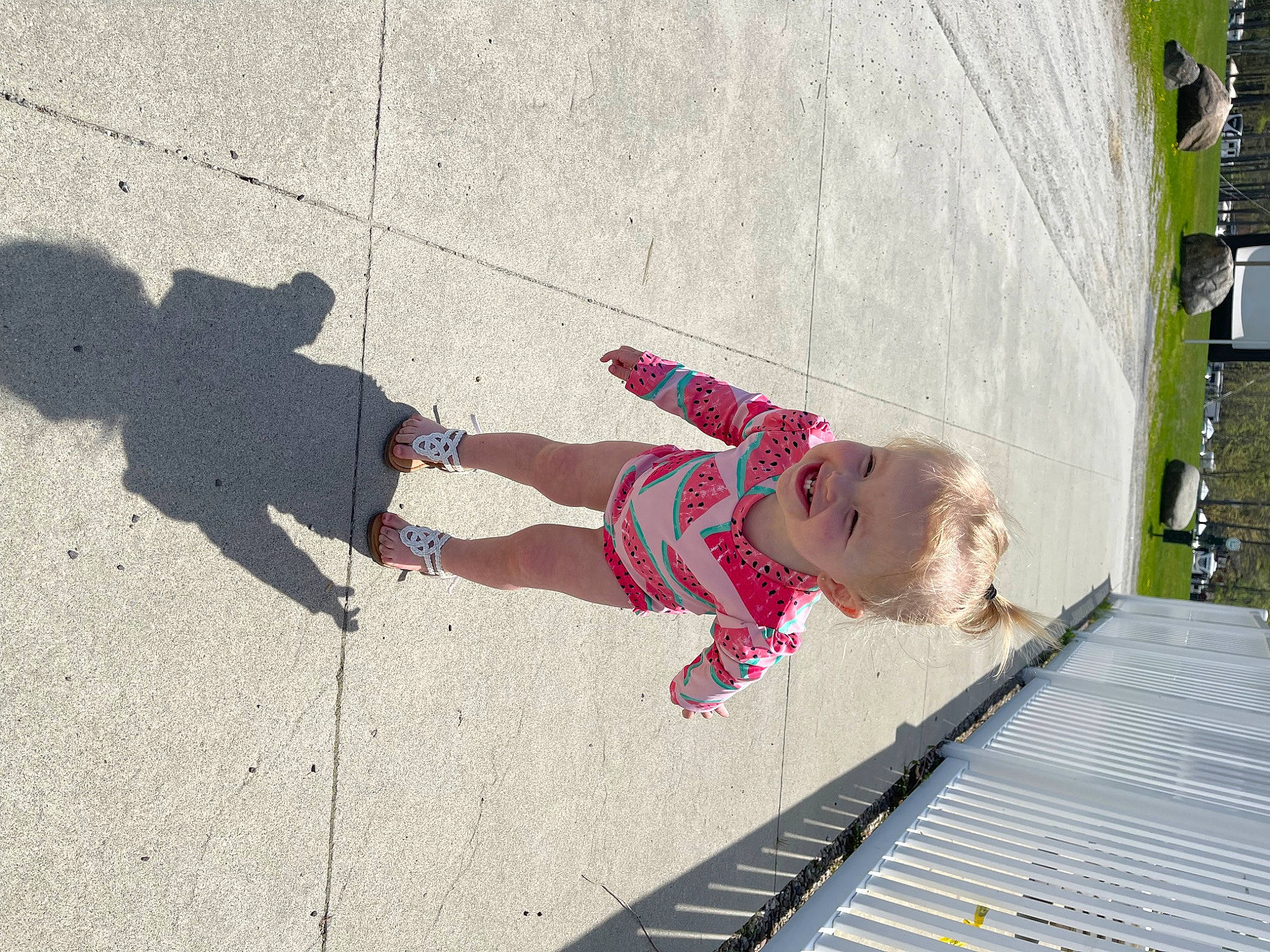 Mckinley is registered to the contest to win money with this photo: asphalt, baby, city, concrete, flooring, fun, human_leg, joy, leisure, pattern, pedestrian, person, plant, recreation, road, road_surface, shadow, sidewalk, thigh, toddler