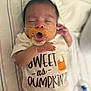 baby, infant, pacifier, sleeping, onesie, text_on_clothing, blanket, striped, hand, face, closeup, cute, resting, newborn, child, indoors, soft_lighting, peaceful, portrait, young
