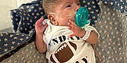 Psalms is registered to the contest to win money with this photo: baby, newborn, hospital, pacifier, onesie, blanket, star_pattern, milestone_sign, mickey_mouse, infant, face, hand, foot, medical_tube, lying_down, cute, child, sleepy, baby_clothing, indoor