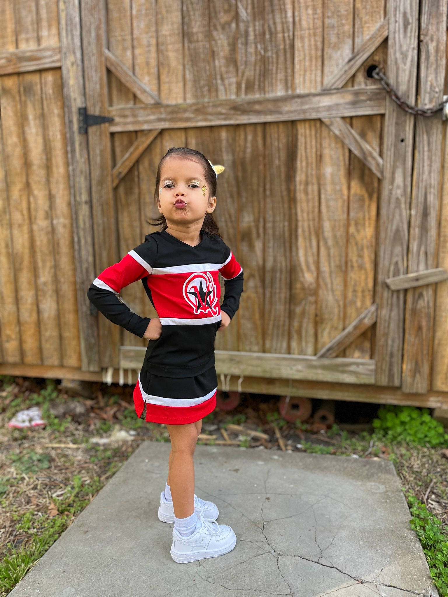 Adriana is registered to the contest to win money with this photo: cheerleading_uniform, electric_blue, fence, grass, happy, human_leg, jersey, knee, magenta, person, plant, sleeve, sportswear, street_fashion, t_shirt, thigh, toddler, trunk, uniform, waist
