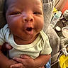 Milo is registered to the contest to win money with this photo: baby, infant, face, hands, onesie, clothing, expression, indoor, bottle, furniture, blanket, person, newborn, cute, child, portrait, cozy, home, closeup, smile