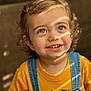 toddler, child, smile, curly_hair, blue_eyes, yellow_shirt, denim_overalls, portrait, sunlight, indoor, happy, cute, young_child, face, person, clothing, casual, expression, closeup, baby