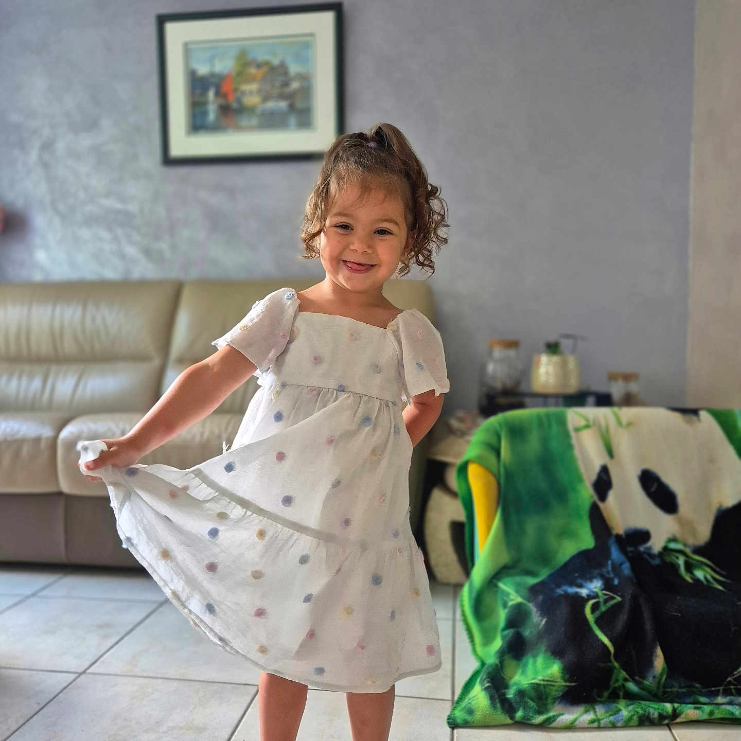Hel participe au concours pour gagner de l'argent avec cette photo : air_conditioner, barefoot, blanket, casual, child, curly_hair, dress, furniture, girl, happy, home_interior, living_room, painting, panda, person, playful, portrait, smile, sofa, tile_floor