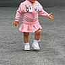 toddler, child, pink_clothing, headband, flower, smiling, walking, outdoor, pavement, sneakers, white_shoes, cute, happy, young_child, playful, shorts, jacket, casual_wear, person, fun