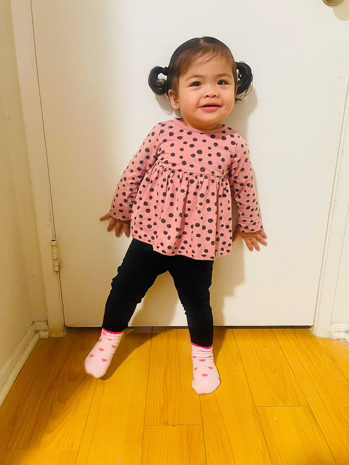 Eleanor is registered to the contest to win money with this photo: baby_toddler_clothing, day_dress, flooring, happy, hardwood, human_leg, joy, knee, magenta, neck, one_piece_garment, pattern, person, shoe, shoulder, sleeve, smile, sock, thigh, toddler