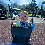 Tobias joined the competition — help win amazing prizes! child, toddler, swing, playground, smiling, happy, outdoor, daylight, park, clothing, holding, green, sippy_cup, sky, trees, slide, play_equipment, fun, joy, person