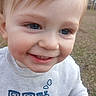 toddler, child, smiling, close_up, blue_eyes, light_hair, sweater, train_design, outdoor, grass, happy, face, portrait, baby, cute, young_child, person, nature, daylight, casual_clothing