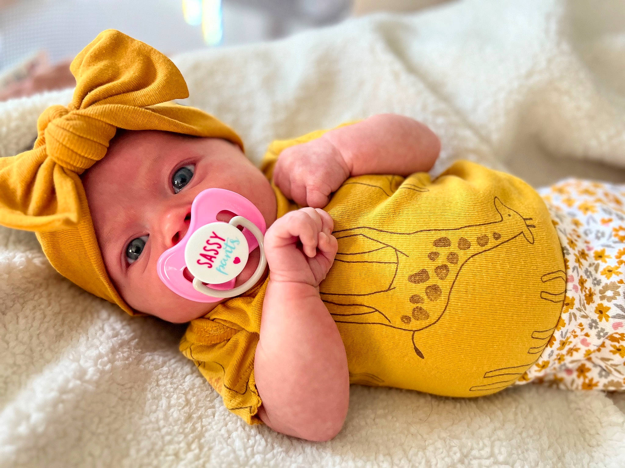 Brooklynn is registered to the contest to win money with this photo: arm, baby, baby_sleeping, baby_toddler_clothing, cheek, comfort, eye, finger, hand, happy, head, headgear, headwear, human_body, nose, orange, person, product, skin, textile