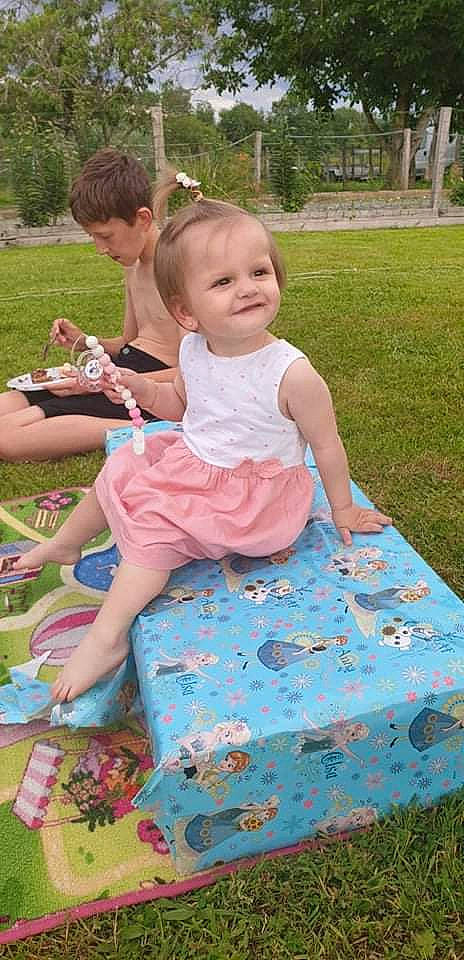 Nora a rejoint le concours — aidez-le/la à gagner de superbes lots ! baby, baby_toddler_clothing, child, dress, event, fun, grass, happy, joy, lawn, leisure, pattern, people_in_nature, person, photograph, pink, plant, recreation, sitting, snapshot