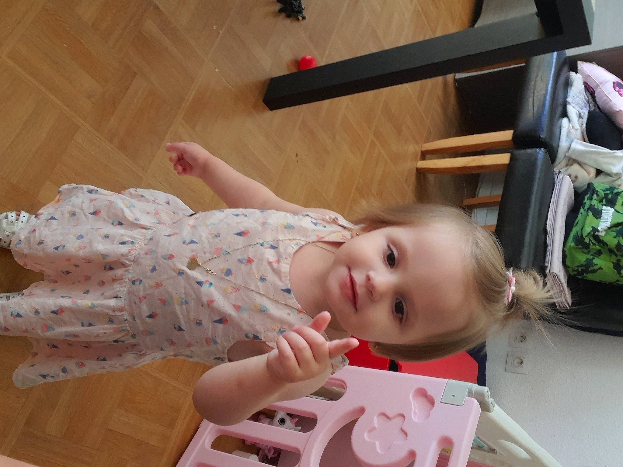 Nora a rejoint le concours — aidez-le/la à gagner de superbes lots ! baby, baby_toddler_clothing, cheek, child, dress, finger, flooring, fun, green, happy, hardwood, human_leg, joy, person, pink, room, sitting, skin, smile, toddler