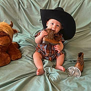 Jace joined the competition — help win amazing prizes! baby, barefoot, belt_buckle, boot, chewing, child, cowboy_hat, cute, footwear, green_backdrop, hat, indoor, infant, plaid_clothing, plush_toy, portrait, sitting, smiling, toy, western_theme