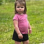 black_shorts, child, daylight, grass, greenery, kite, nature, outdoor, person, pink_shirt, ponytails, serious_face, shoes, short_hair, socks, standing, summer, toddler, toy, young_child
