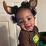 toddler, child, smiling, face, curly_hair, brown_clothing, reindeer_ears, indoor, person, holding, door, cute, happy, portrait, baby, costume, accessory, black_hair, hand, playful