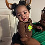 Jakodah is registered to the contest to win money with this photo: toddler, child, baby, smiling, person, holding, costume, reindeer_ears, curly_hair, indoor, door, brown_clothing, green_shirt, bracelet, glasses, tag, cute, happy, portrait, family