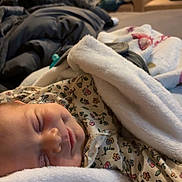 Ivy is registered to the contest to win money with this photo: baby, bed, blanket, child, comfort, cozy, cute, fabric, face, home, indoors, infant, patterned_clothing, peaceful, pillow, rest, sleeping, smile, soft, warm_light