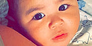 Jeremiah is registered to the contest to win money with this photo: baby, child, face, eyes, infant, person, clothing, cute, skin, portrait, closeup, elephant_print, white, blue, sleeveless, snuggling, curly_hair, indoors, soft_light, young