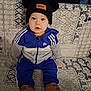 Timéo a rejoint le concours — aidez-le/la à gagner de superbes lots ! toddler, child, blue_tracksuit, hat, pom_poms, sitting, couch, patterned_couch, indoor, footwear, brown_shoes, face, eyes, expression, casual_clothing, hoodie, young_child, person, portrait, cute