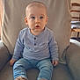 baby, child, blue_eyes, sitting, armchair, jeans, purple_shirt, shoes, indoor, cozy, curious, young_child, portrait, furniture, casual_clothing, comfortable, home, looking_away, cute, soft_lighting