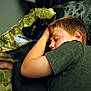 boy, dog, sleeping, couch, blanket, pillow, indoor, child, pet, cozy, rest, nap, friendship, arm, green, black_dog, casual_clothing, relaxation, home, intimate