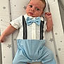 Cruz is registered to the contest to win money with this photo: baby, infant, child, blue_bow_tie, suspenders, white_shirt, blue_pants, star_pattern, changing_pad, cute_outfit, lying_down, curious_expression, indoor, soft_lighting, newborn, small_hands, bare_feet, portrait, person, face