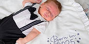 Cruz is registered to the contest to win money with this photo: baby, sleeping, infant, blanket, tuxedo, bow_tie, white, black, cute, face, arm, clothing, soft, newborn, portrait, peaceful, indoors, child, resting, bed