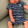 baby, infant, child, striped_clothing, blue_outfit, shorts, polo_shirt, couch, sofa, gray_fabric, barefoot, cute, face, skin, human, sitting, indoors, expression, young, person