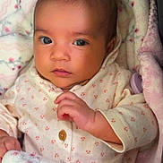 Itzel joined the competition — help win amazing prizes! baby, infant, blanket, clothing, face, hand, newborn, cute, portrait, indoors, soft_texture, sleepwear, child, expression, skin, eyes, person, warm, cozy, lying_down