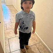 Uriel is registered to the contest to win money with this photo: child, boy, cap, backward_cap, shirt, spiderman, hallway, tile_floor, brown_shoes, curious, standing, indoor, casual_clothing, young, person, portrait, wide_eyes, looking_up, short_sleeves, pants