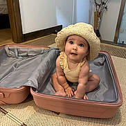 Elena participe au concours pour gagner de l'argent avec cette photo : baby, child, suitcase, hat, straw_hat, indoor, floor, rug, curious, seated, cute, looking_up, pink, travel, open_suitcase, woven_rug, home, innocent, small, adorable