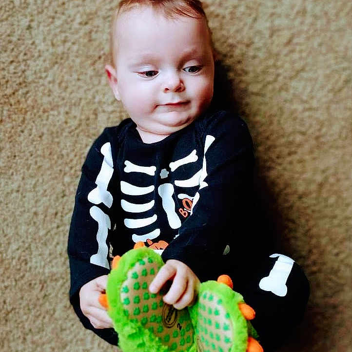 Sigfred is registered to the contest to win money with this photo: baby, bodypart, clothing, coat, face, finger, footwear, hand, happy, head, jacket, pants, person, photography, portrait, shoe, sitting, smile, t_shirt, toy