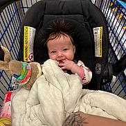 Noelle Ryann is registered to the contest to win money with this photo: aisle, arm, baby, blanket, car_seat, child, clothing, cute, fabric, hair, happy, indoor, infant, person, seat, shopping_cart, smiling, store, tattoo, toy