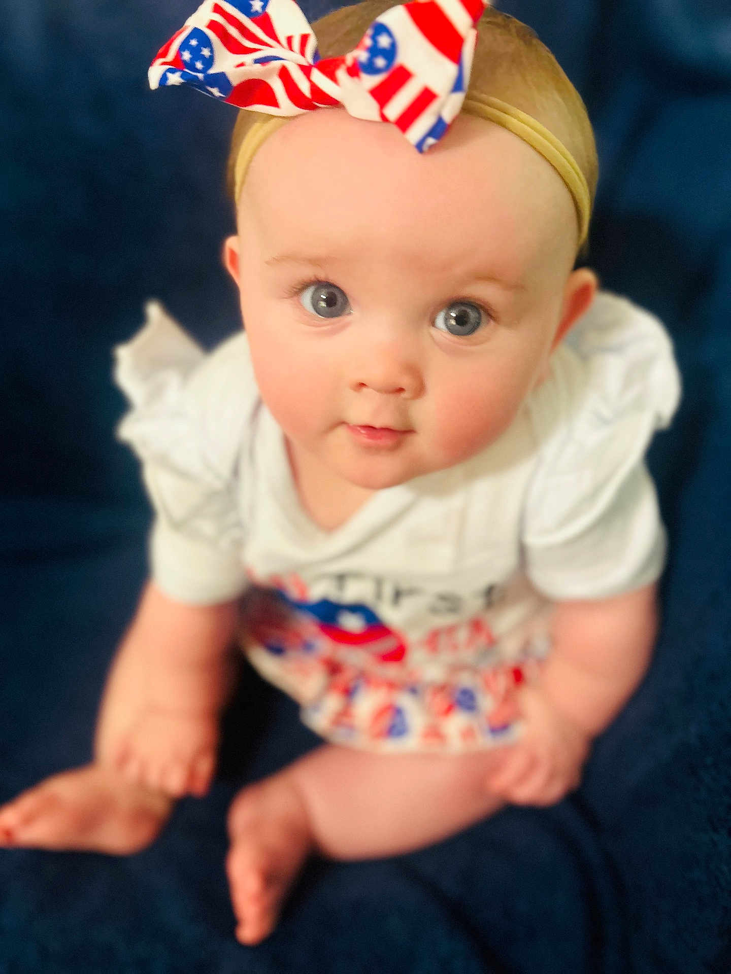 Ezlynn is registered to the contest to win money with this photo: baby, child, infant, sitting, blue_eyes, headband, bow, white_clothing, red, blue, skin, cute, portrait, indoors, blanket, chubby, gaze, front_view, person, young