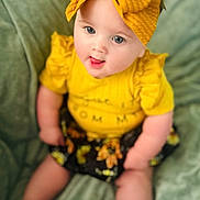 Ezlynn joined the competition — help win amazing prizes! baby, child, yellow_bow, yellow_top, ruffled_sleeves, black_floral_skirt, sitting, tongue_out, blue_eyes, soft_blanket, indoor, cute, portrait, infant, headband, playful, smiling, person, closeup, happy