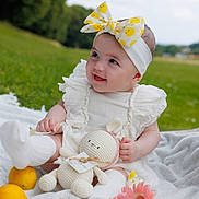 Sophie a rejoint le concours — aidez-le/la à gagner de superbes lots ! baby, child, outdoor, grass, blanket, headband, bow, toy, crocheted_toy, lemons, flowers, pink_flowers, white_clothing, socks, smiling, happy, nature, fruit, portrait, cute